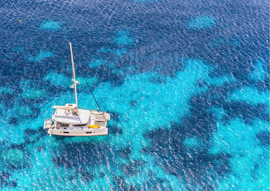 Catamarano a vela ormeggiato in una cala incontaminata del Mediterraneo
